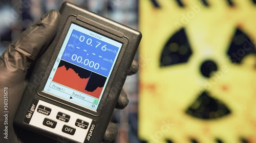 Scientist holds a Geiger counter to measure the microSieverts per hour of radiation at nuclear facility. Nuclear disaster and radiation fallout concepts.  photo