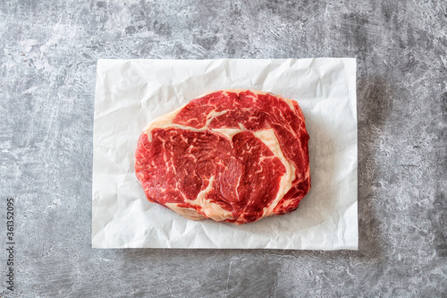 Entrecote (Ribeye) Steak auf Pergamentpapier mit grauem Untergrund photo