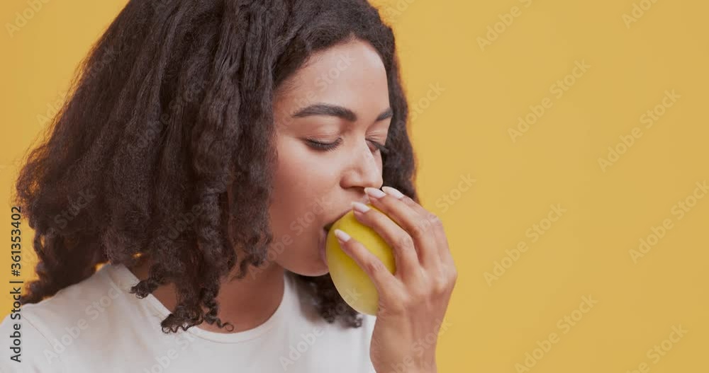 African american girl biting fresh apple and enjoying it African american girl biting fresh apple and enjoying it