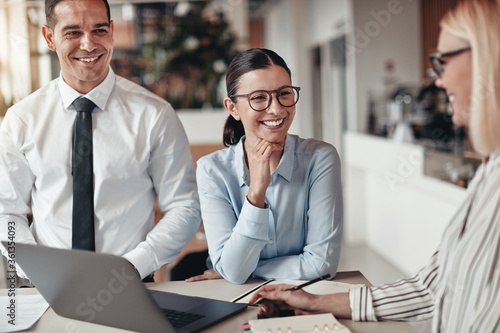 Three smiling coworkers talking together in an office