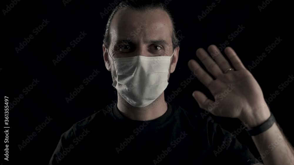 Young handsome guy with face mask is hand weaving on black background, studio shot. Young handsome guy with face mask is hand weaving on black background, studio shot.