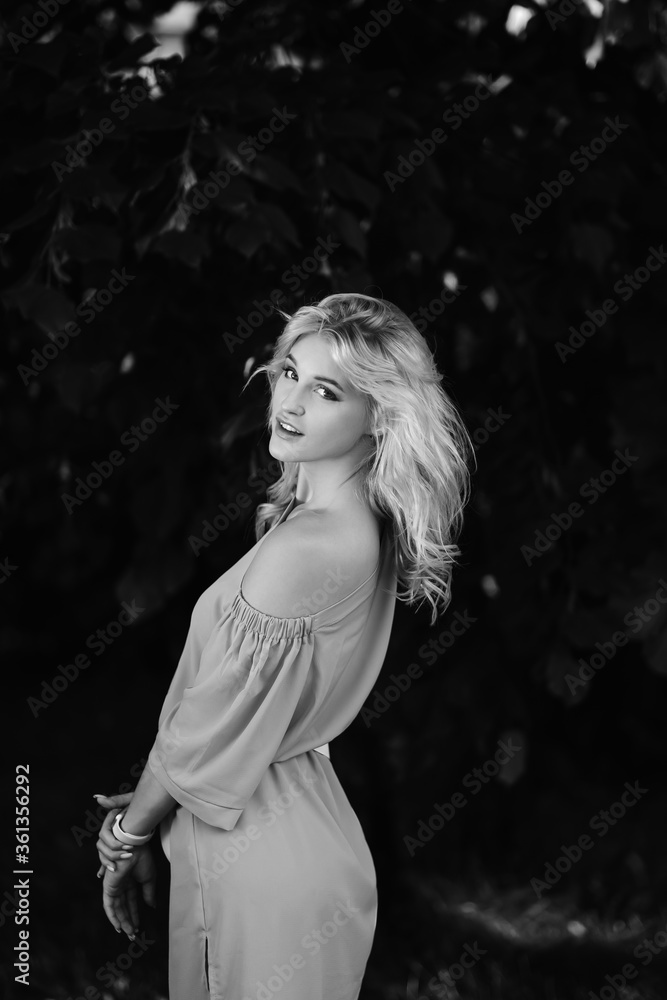 Portrait of a young beautiful girl 21 years old in a blue summer dress with a white belt bag. The woman smiles. Beautiful lips and eyes. Long loose hair. Portrait of a young beautiful girl 21 years old in a blue summer dress with a white belt bag. The woman smiles. Beautiful lips and eyes. Long loose hair.