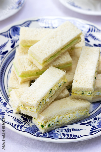 Obraz na płótnie Afternoon tea in the garden, finger sandwiches with cucumber and egg salad and tea on a light background. w salonie