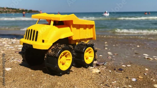 A yellow toy truck parked on the sand while tiny waves are approaching, Kavatsi, Sozopo, Bulgaria photo