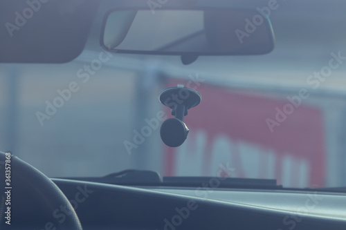 Salon auto rearview mirror holder for phone steering wheel windshield. Side view through glass in sunlight with a blurred background.