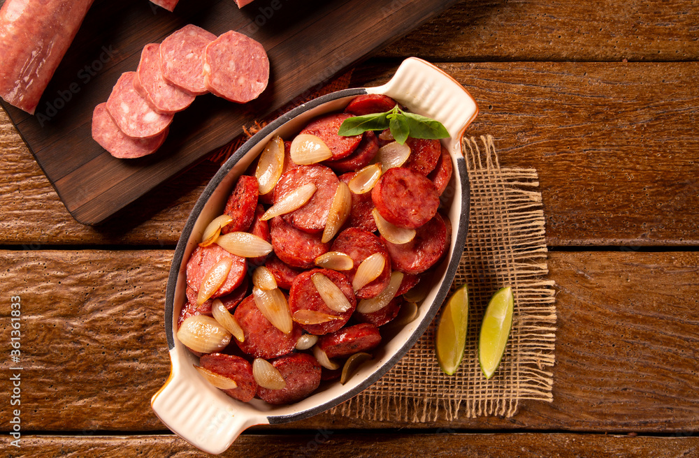 Smoked sausage with bread and onions on wood background. Snack appetizer calabrese sausage with onion.