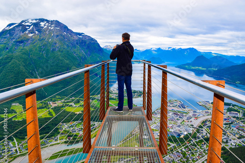 Hiking Rampestreken. Tourist man on the Rampestreken Viewpoin. Panoramic landscape Andalsnes city in Norway. photo