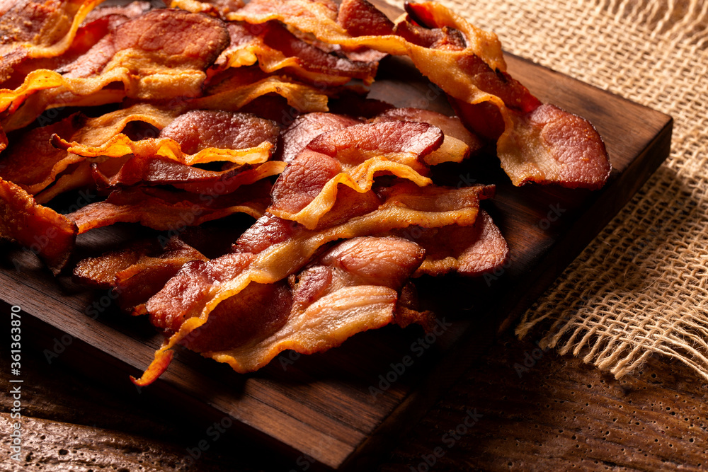 fried bacon strips on rustic wooden board