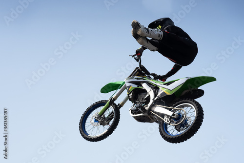 Obraz na płótnie man in a helmet performs a stunt in the air on a motorcycle w salonie