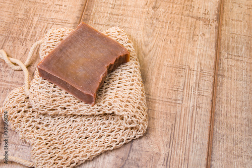 cocoa soap made from natural ingredients on a knitted washcloth, homemade soap on a wooden background, zero life-style waste, cocoa bar on a cotton thread washcloth