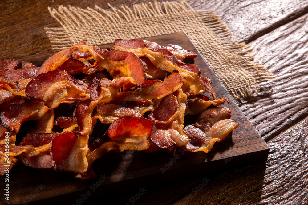fried bacon strips on rustic wooden board fried bacon strips on rustic wooden board