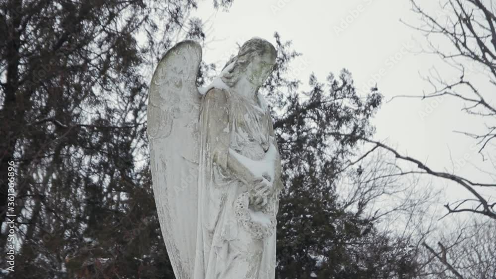 Stone statue of an angel in a cemetery in winter. Monument in the snow Stone statue of an angel in a cemetery in winter. Monument in the snow