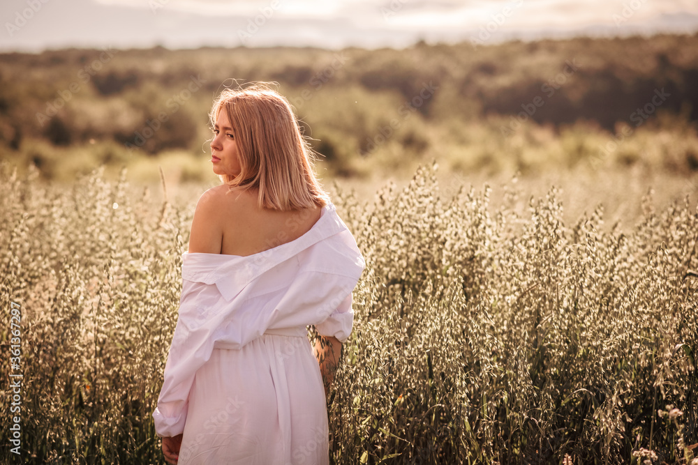 Young busty girl in a white dress on an oat field. Young busty girl in a white dress on an oat field.