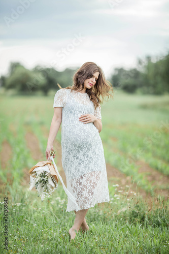 Portrait of a young beautiful pregnant woman. A pregnant woman with a bouquet of flowers walks in the park. Motherhood.