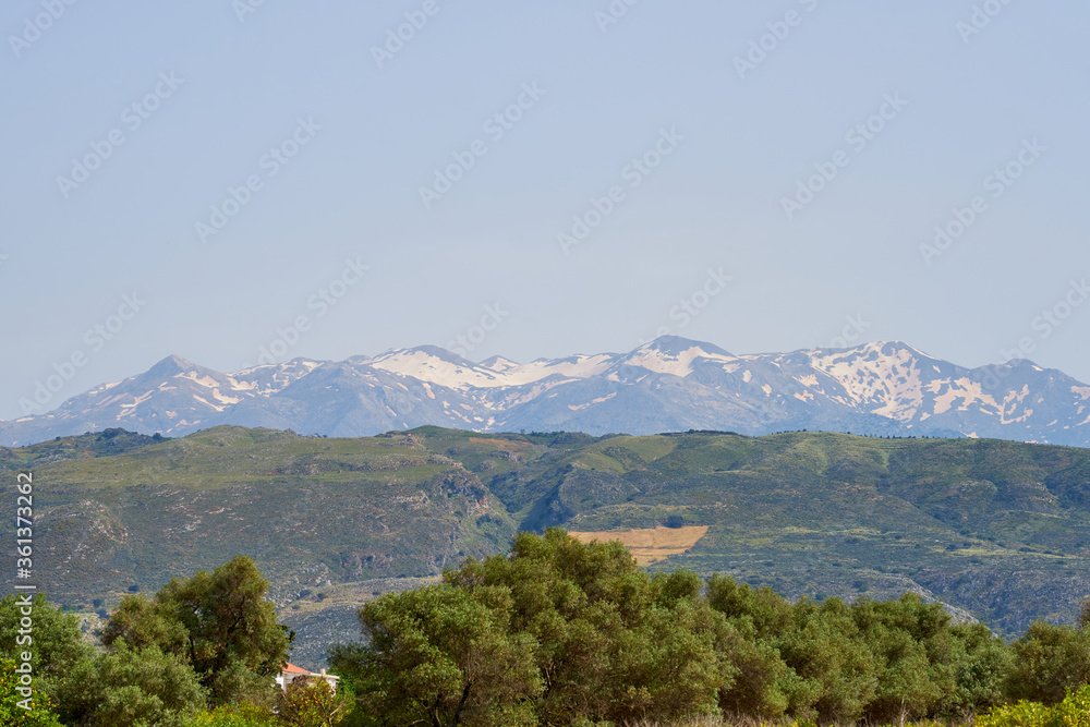 Trees, hills and mountains against a clear blue sky in Crete, Greece. Copy space.