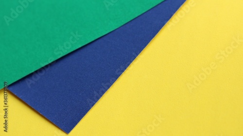 stationery background from sheets of blue, green and yellow thick paper with a dotted texture carelessly stacked on top of each other