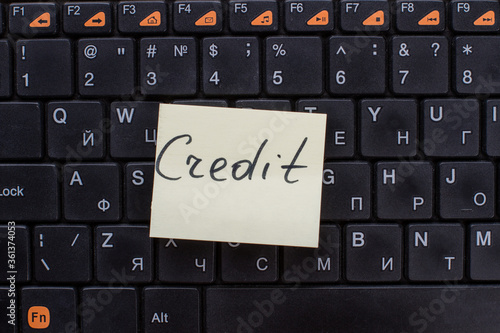 Credit words written on note paper. Note on the black keyboard.