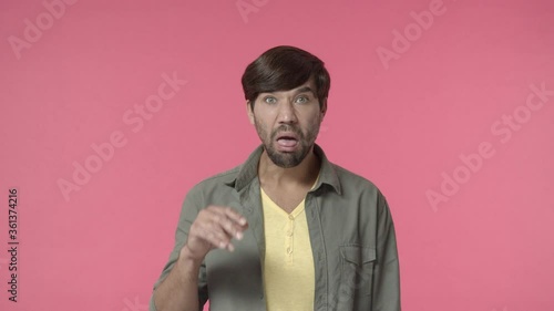 Annoyed and bored, rude young man mocking over boring person, mumbling and making blah blah gesture with grimace and dislike, bothered by uninteresting conversation, pink background