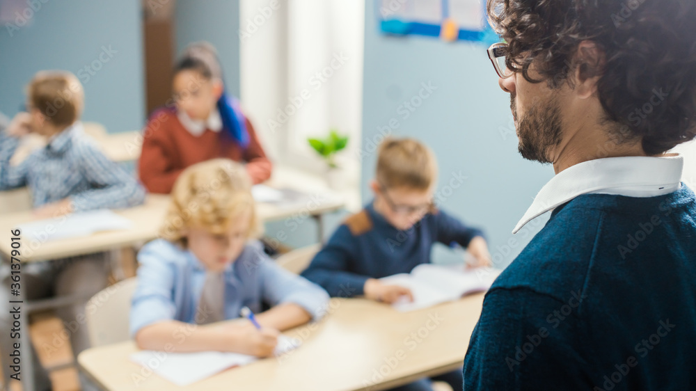 Over the Soulder Shot of Teacher Explaining Lesson to Classroom Full of Diverse Bright Children, In Elementary School Group of Smart Multiethnic Kids Learning Science and Creative Thinking. Over the Soulder Shot of Teacher Explaining Lesson to Classroom Full of Diverse Bright Children, In Elementary School Group of Smart Multiethnic Kids Learning Science and Creative Thinking.