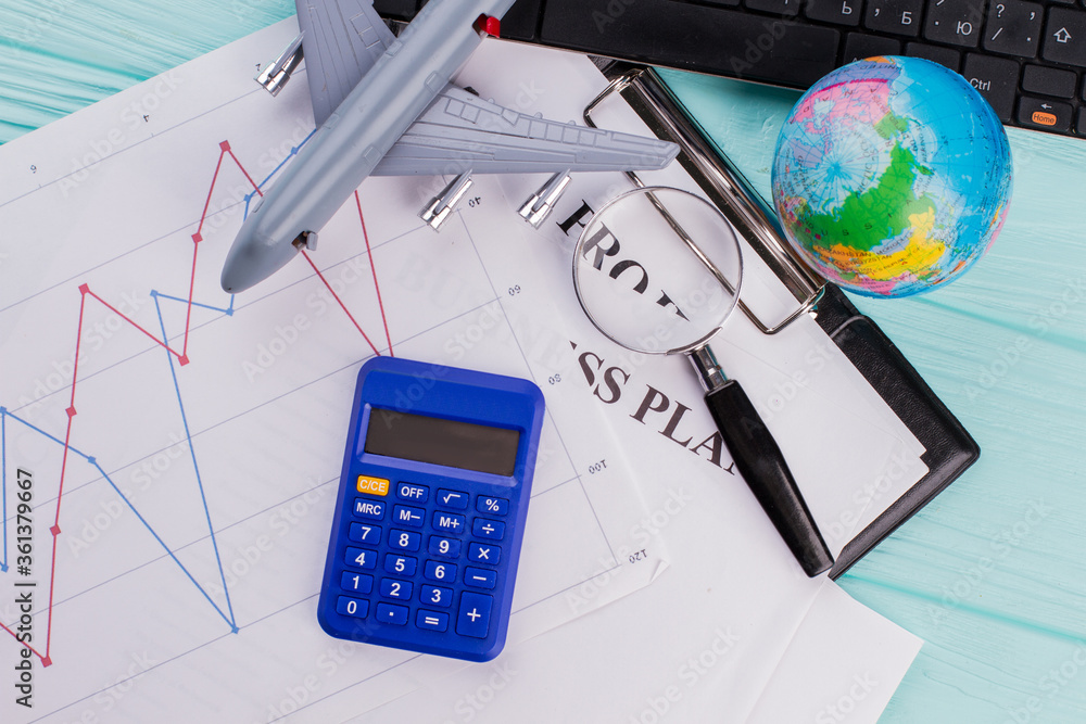 Bunch of office supplies. Keyboard, globe, airplane, sheets and calculator on a blue background. Concept of travel planning, Bunch of office supplies. Keyboard, globe, airplane, sheets and calculator on a blue background. Concept of travel planning,