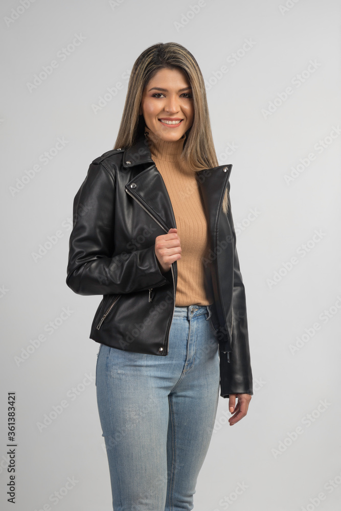 portrait of young beautiful latin woman with leather jacket, jeans and brown blouse, smiling and posing, studio portrait of young beautiful latin woman with leather jacket, jeans and brown blouse, smiling and posing, studio