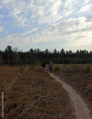 Man and woman walk on path in forest at spring day