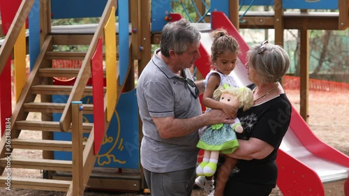 Nonni bianchi giocano con i nipoti di una altra etnia nel parco giochi di una pineta  photo