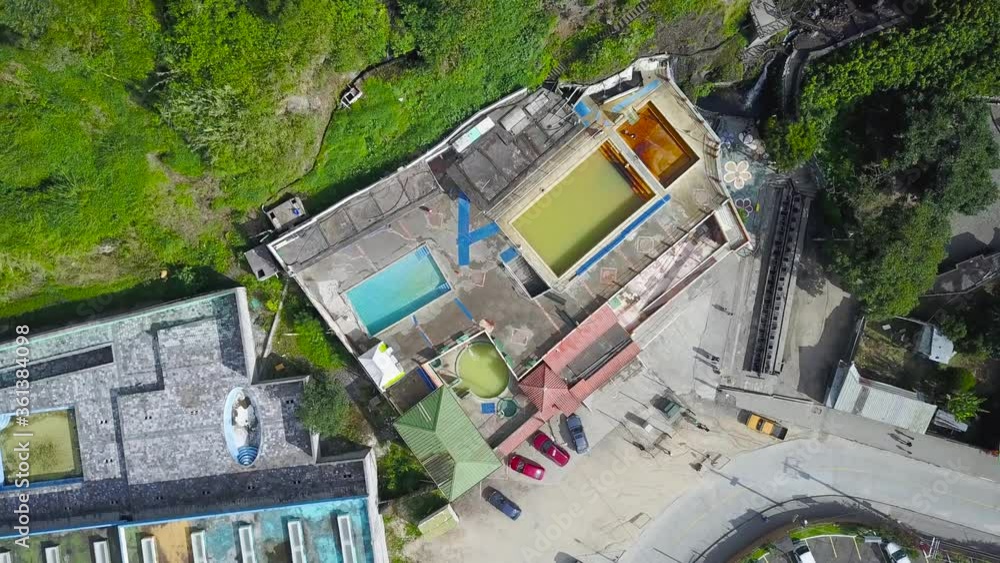 Circling Aerial Drone Overhead Shot From Above Of Aquatic Complex Besides A Long Beautiful Waterfall Coming Out Of Green Mountain With Cars Parked On Parking Lot Outside Hot Spring Pools Circling Aerial Drone Overhead Shot From Above Of Aquatic Complex Besides A Long Beautiful Waterfall Coming Out Of Green Mountain With Cars Parked On Parking Lot Outside Hot Spring Pools