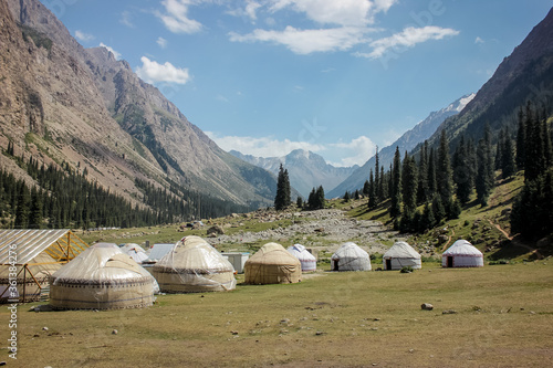 Mountain landscape photo with Asian yurts, horse, trees and stone. Ethnic village with high rocks on the background.