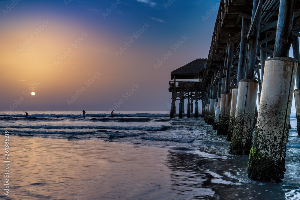 Sunrise at beach pier over ocean