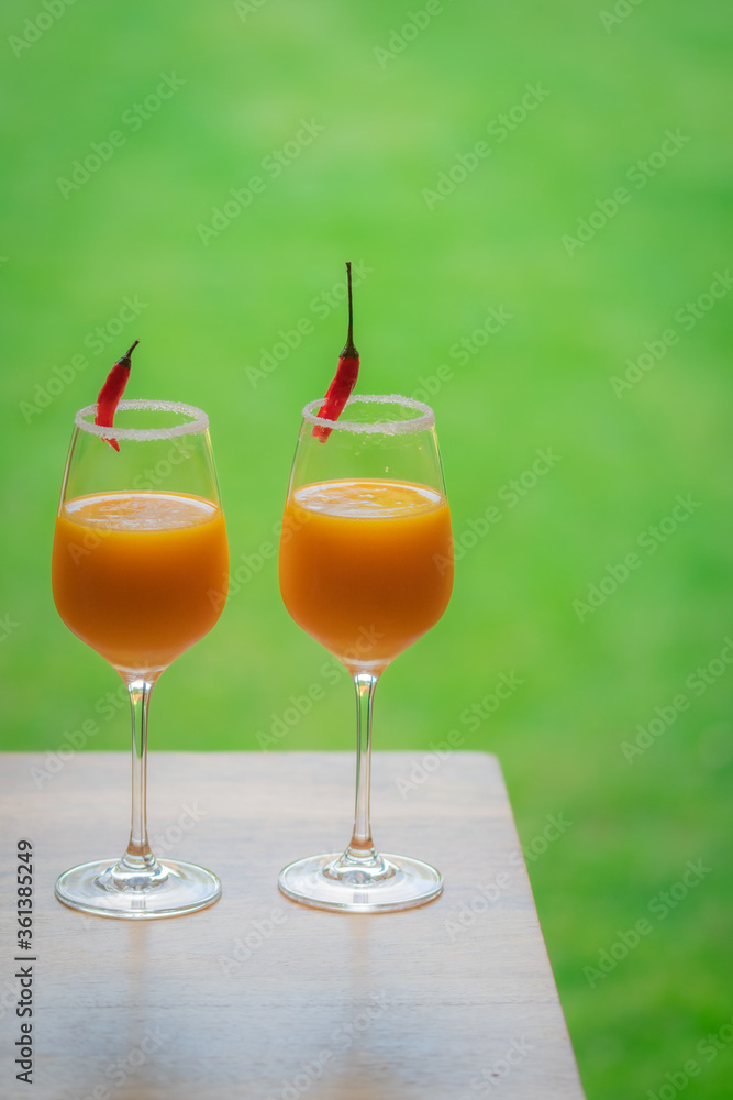 Top down view of cocktail glasses with orange, mango and red chilli exotic drinks in a British summer home garden. 