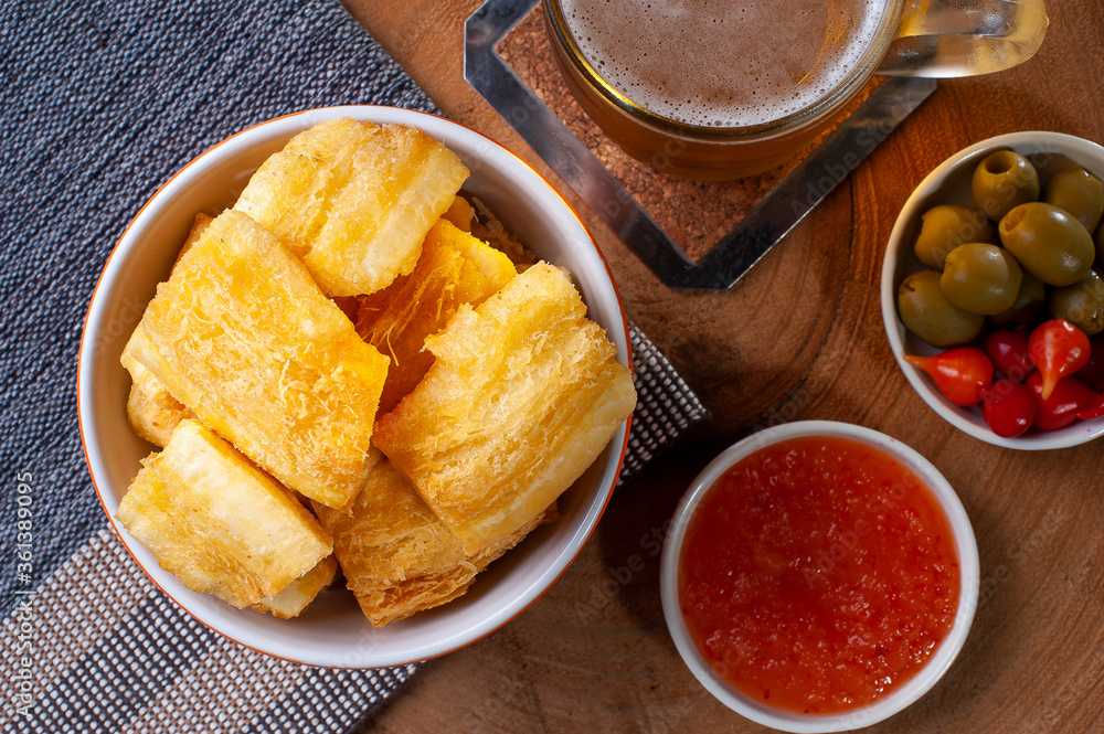.Fried manioc. Traditional Brazilian food dish. Accompanied by pepper jam, olives and pepper pout. Glass of beer. Top view .Fried manioc. Traditional Brazilian food dish. Accompanied by pepper jam, olives and pepper pout. Glass of beer. Top view