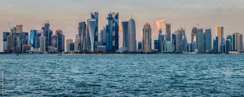 Doha (capital of Qatar) skyline in Corniche daylight view with clouds in the sky and Arabic gulf in foreground