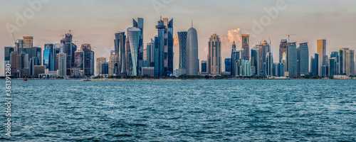 Doha (capital of Qatar) skyline in Corniche daylight view with clouds in the sky and Arabic gulf in foreground