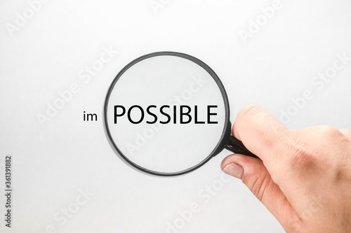 in a magnifying glass, the word impossible, personal development and career growth or change the concept