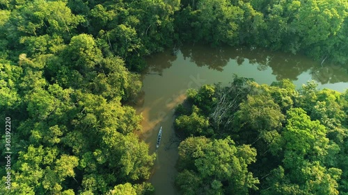 Wide Static Aerial Drone Shot Of Boat Moving Across A Curved River In The Amazon Rainforest Between Green Jungle Flora At Sunset In Cuyabeno Ecuador