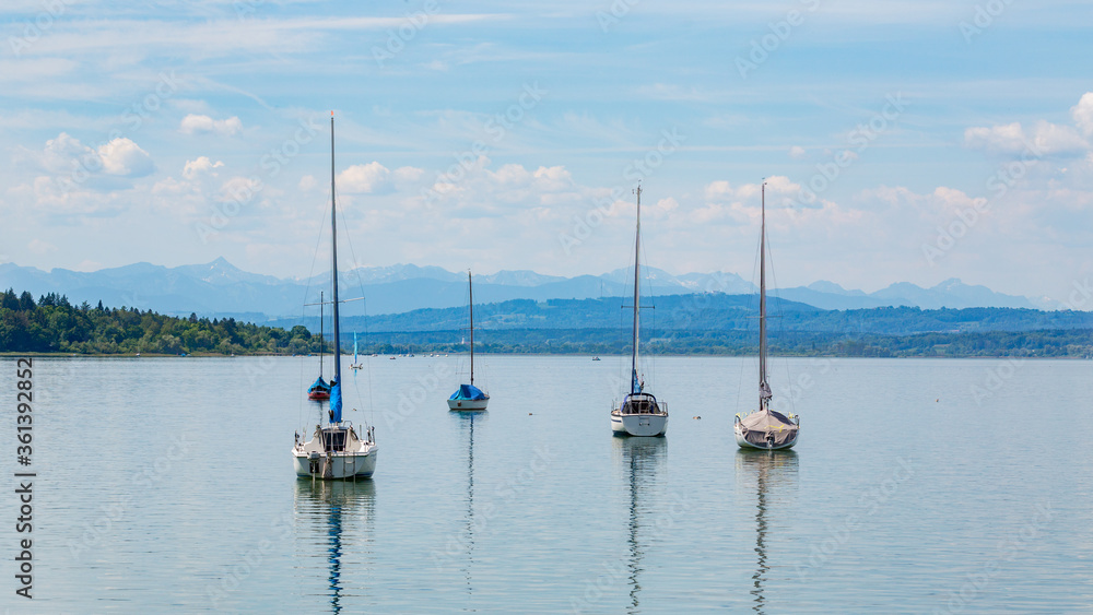Anchoring sailboats at Lake Ammer (Ammersee). Alps on the horizon. Upper bavarian landscape.