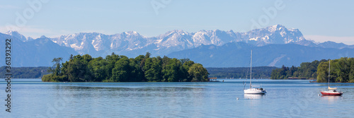 Panorama of Lake Starnberg with Roseninsel, alps and sailboats. Popular travel destination.