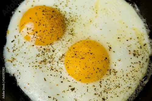 Top view of two fried eggs in a black frying pan