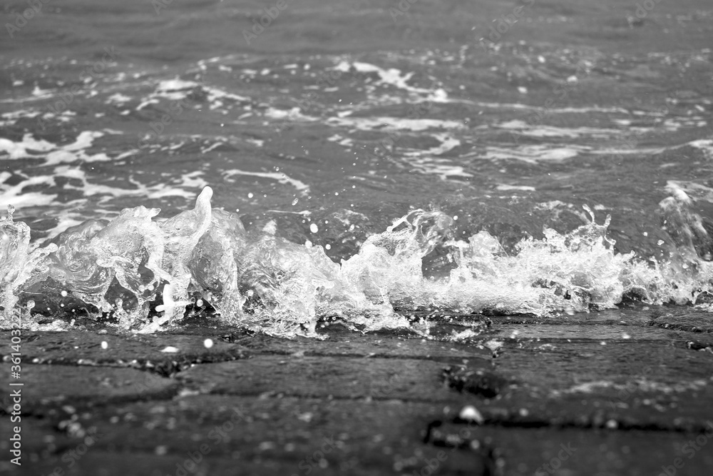 Kleine Welle bricht auf gepflasterten Strand bei Flut