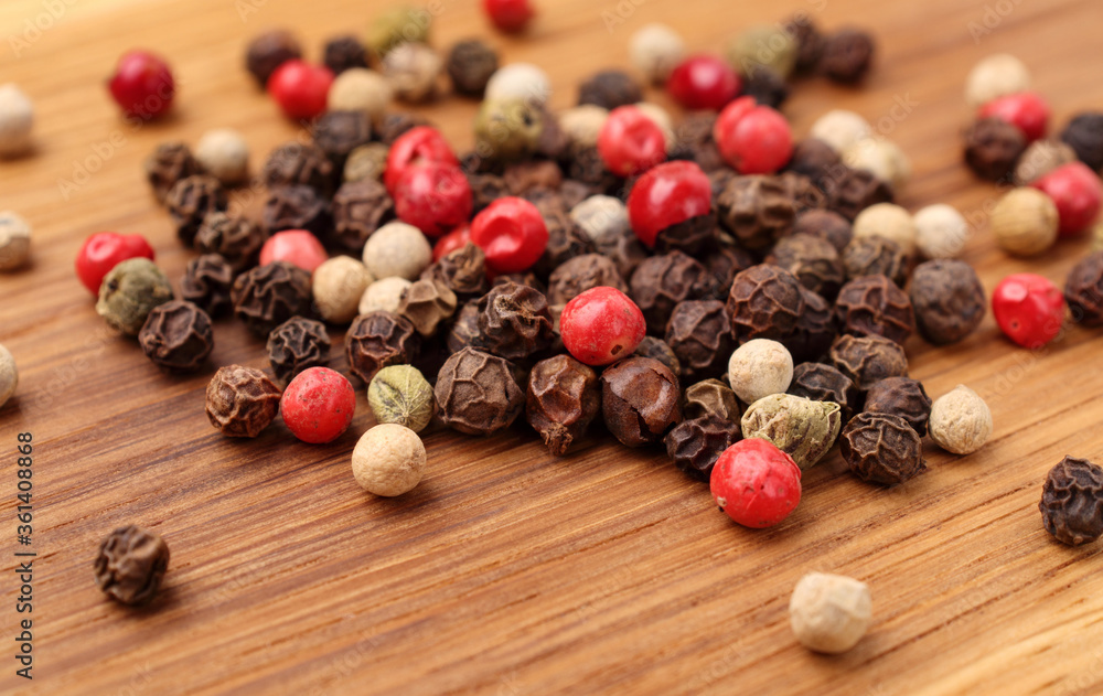 Pile of various peppercorns isolated on wooden board, close up. Mix of black, white, green and red dried peppercorns, close up. Pile of various peppercorns isolated on wooden board, close up. Mix of black, white, green and red dried peppercorns, close up.