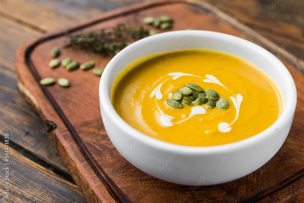 Pumpkin butternut squash cream soup in a bowl against wooden background Pumpkin butternut squash cream soup in a bowl against wooden background