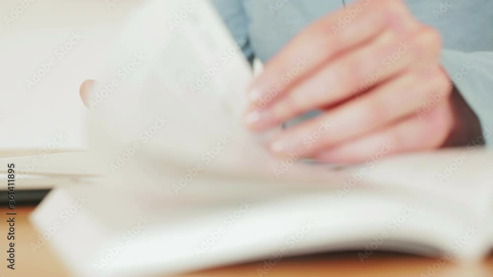 Static closeup, low angle, of a woman studying with a textbook and a tablet computer. Static closeup, low angle, of a woman studying with a textbook and a tablet computer.