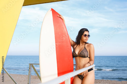 Photography Portrait of a women in swimsuit holding surfboard with copy space for your brand