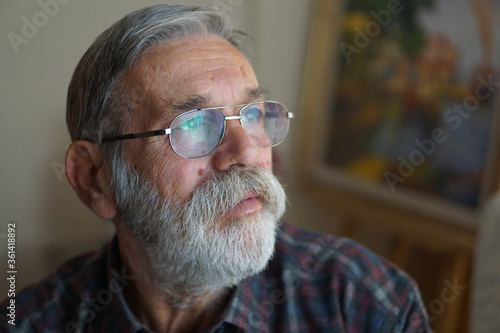 Senior man with beard and glasses looking away. Thinking. 