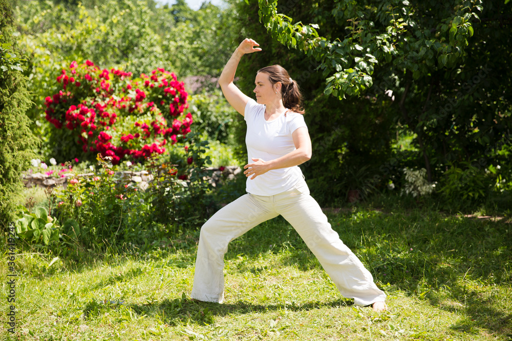 Woman practice Tai Chi Chuan in a park.  Chinese management skill Qi's energy. solo outdoor activities. Social Distancing 