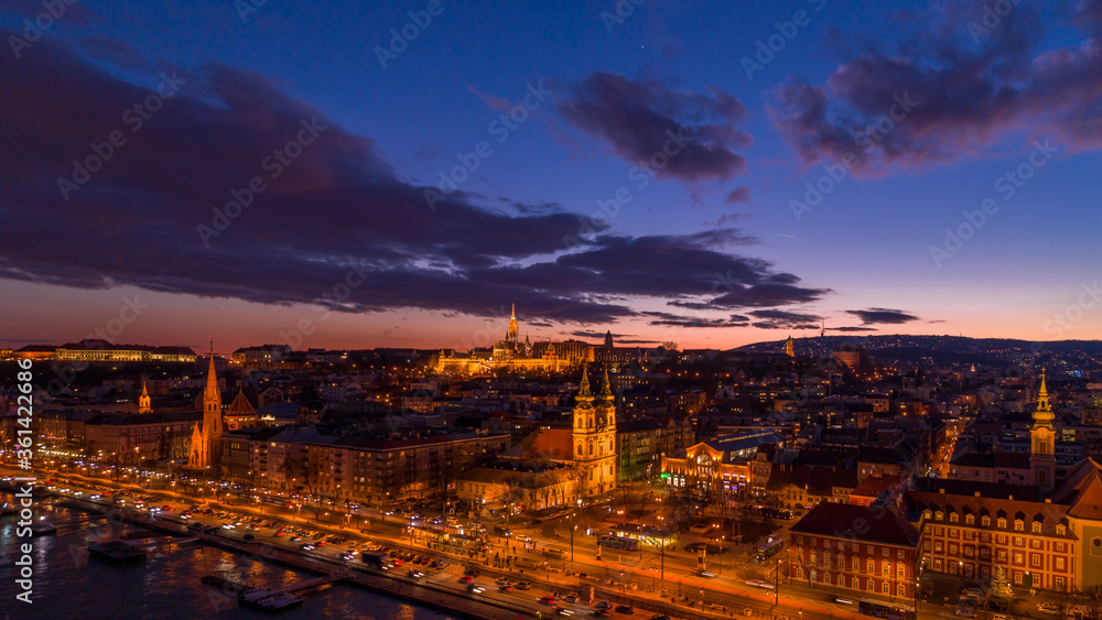 Panoramic aerial drone shot of Matthias Churh, St. Anne Church and market hall by Danube in Budapest sunset