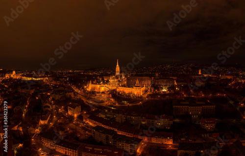Aerial drone shot of Matthias Church with lights on Buda Hill in Budapest evening