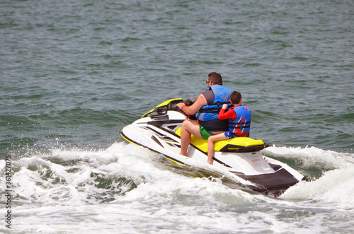 Father and son riding tandem on a jet ski.
