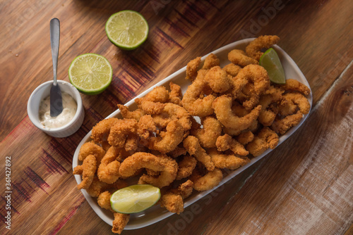 breaded shrimp (Milanesa), served in a dish on a rustic wooden table